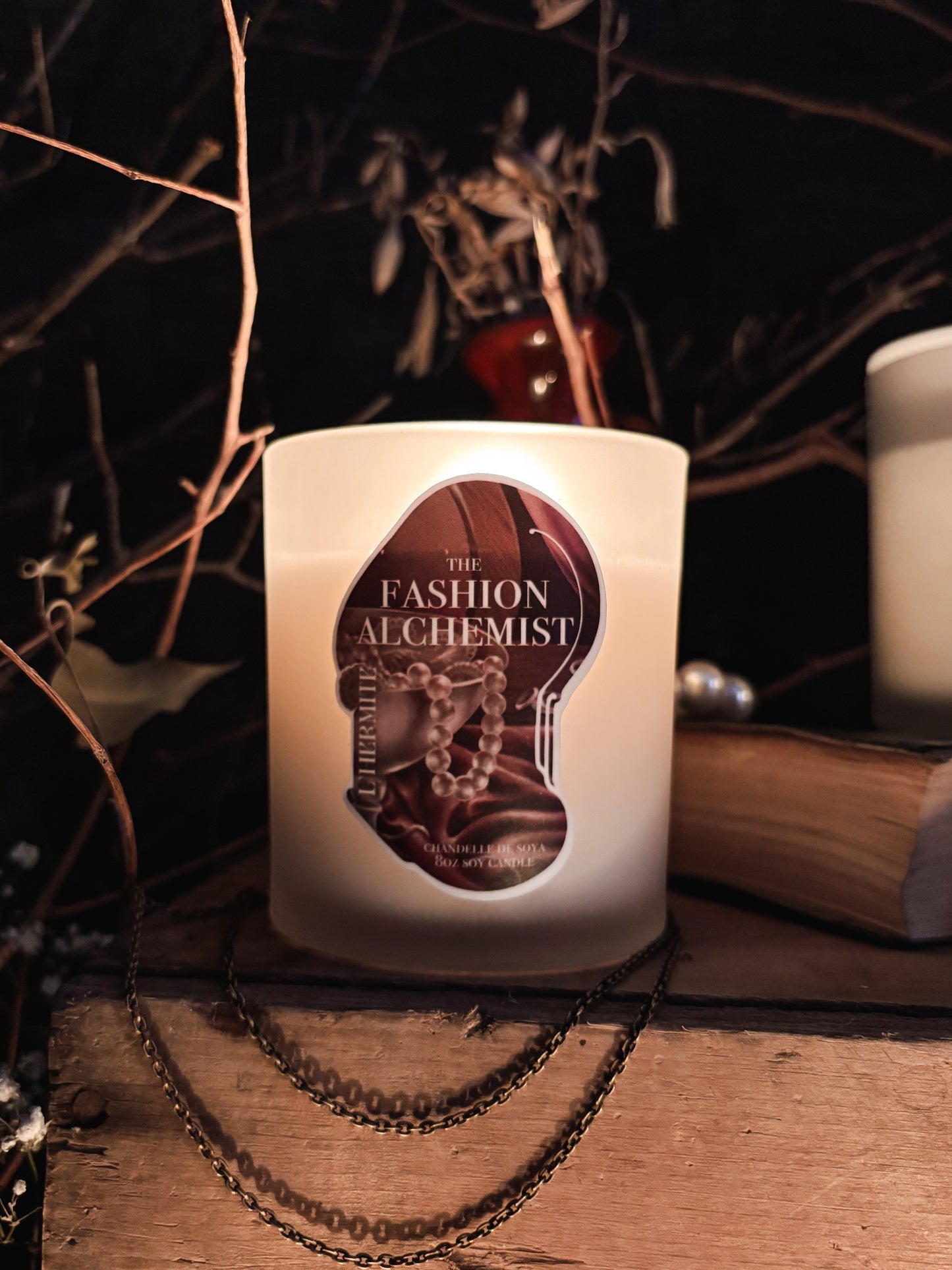 Candle with 'The Fashion Alchemist' label on a dark background