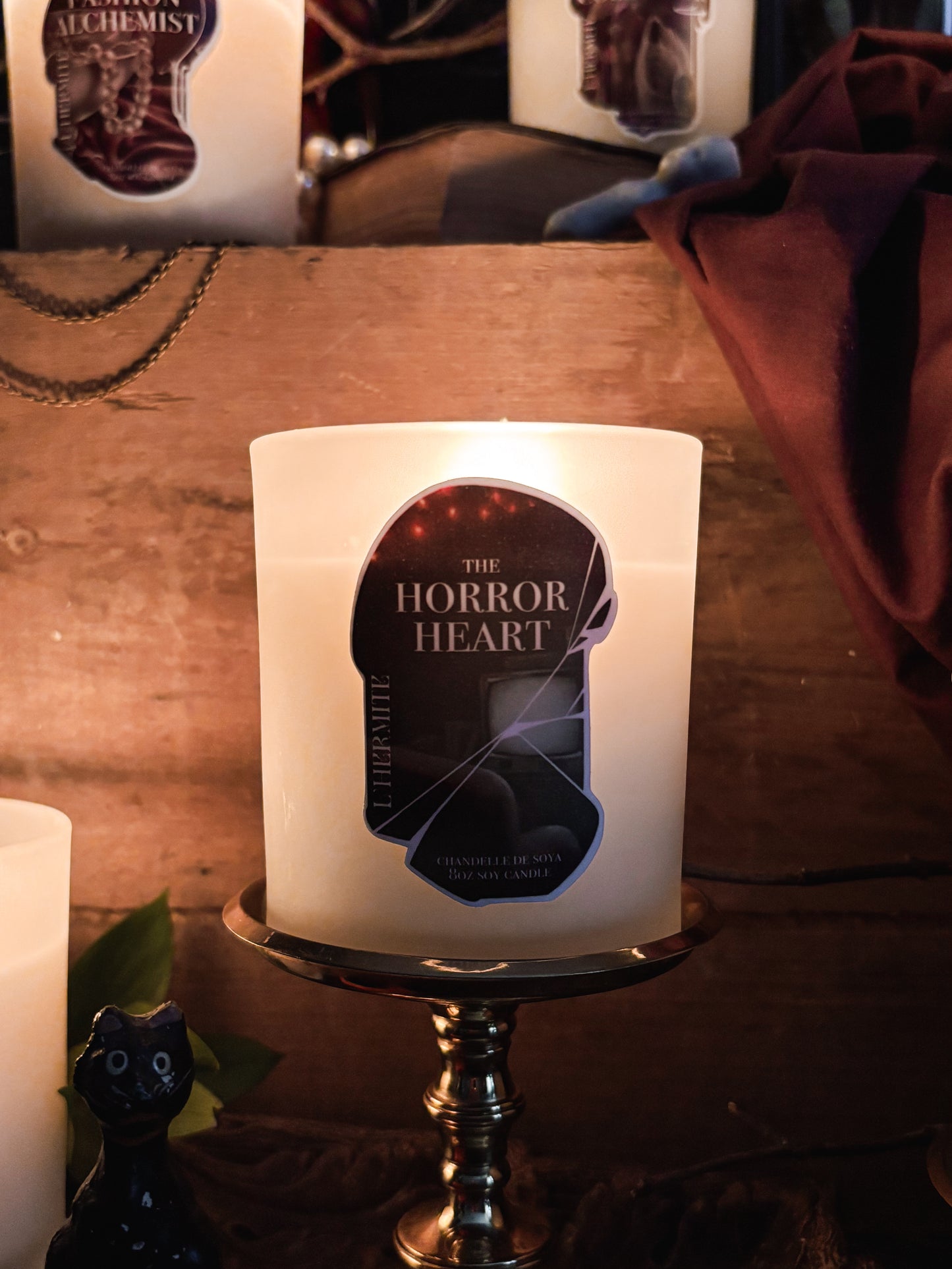 Candle with 'The Horror Heart' label on a wooden surface