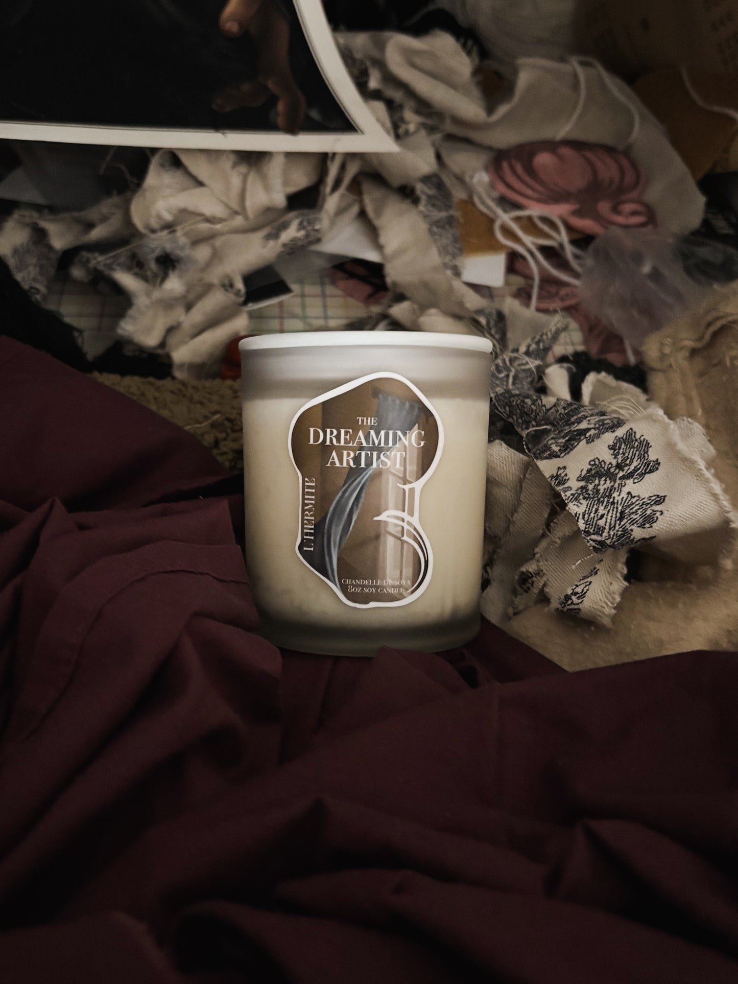 Candle with 'The Dreaming Artist' label on a textured surface