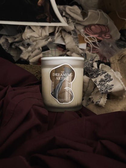 Candle with 'The Dreaming Artist' label on a textured surface