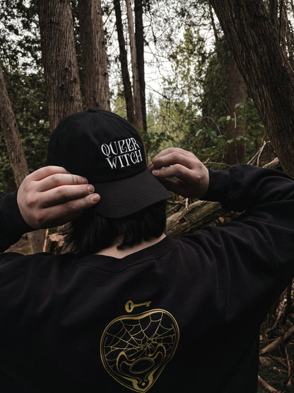 Black embroidered dad hat with 'Queer Witch' stitched in bold lettering. A perfect everyday spell for visibility.