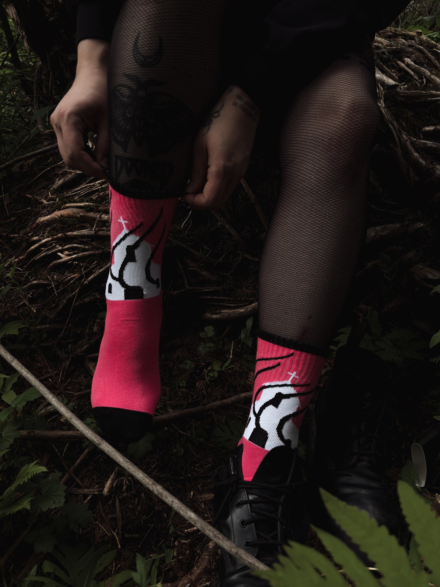 Hot pink socks featuring a flaming church design. Styled with fishnets and platform shoes, walking through mossy woods. A bold statement of queer defiance.