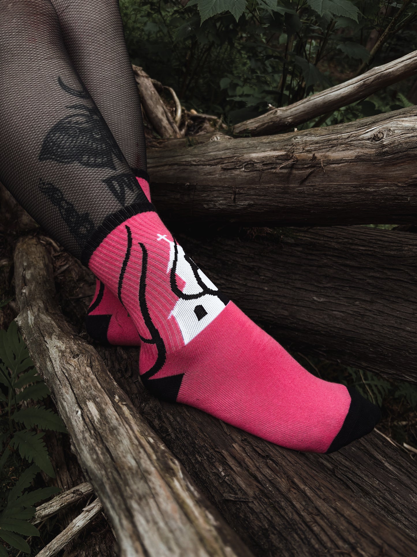 Hot pink socks featuring a flaming church design. Styled with fishnets and platform shoes, walking through mossy woods. A bold statement of queer defiance.