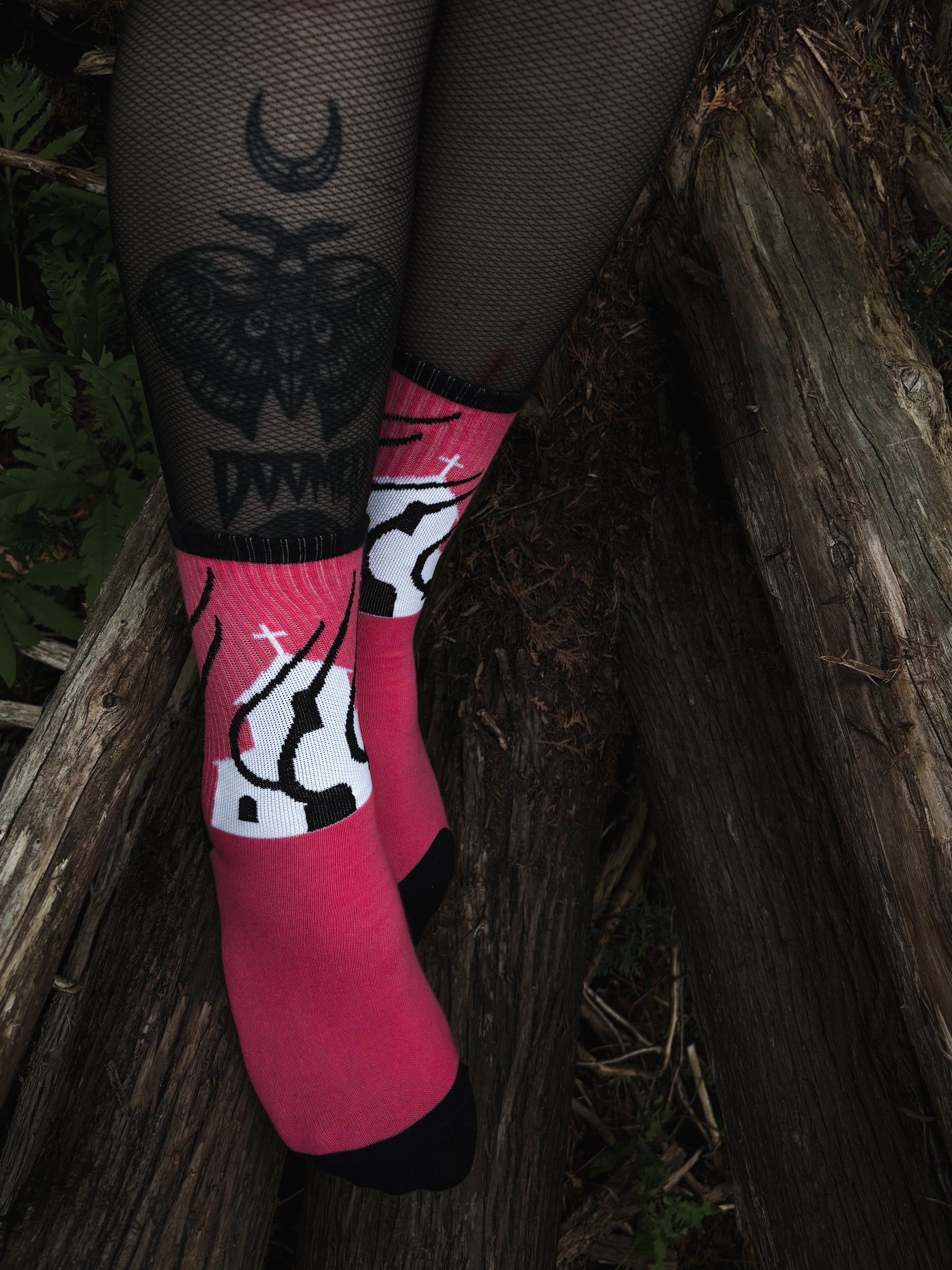 Hot pink socks featuring a flaming church design. Styled with fishnets and platform shoes, walking through mossy woods. A bold statement of queer defiance.
