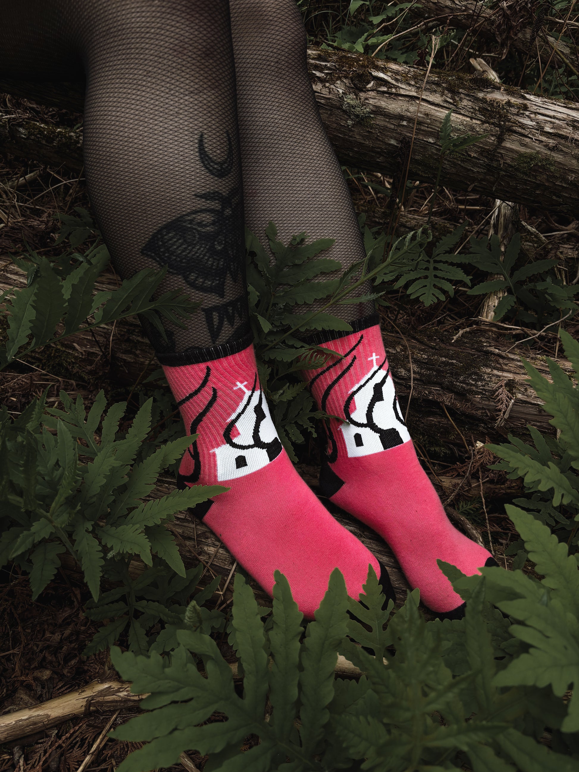 Hot pink socks featuring a flaming church design. Styled with fishnets and platform shoes, walking through mossy woods. A bold statement of queer defiance.