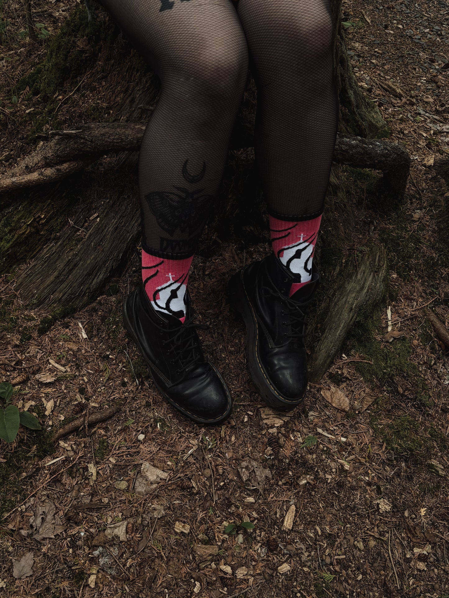 Hot pink socks featuring a flaming church design. Styled with fishnets and platform shoes, walking through mossy woods. A bold statement of queer defiance.