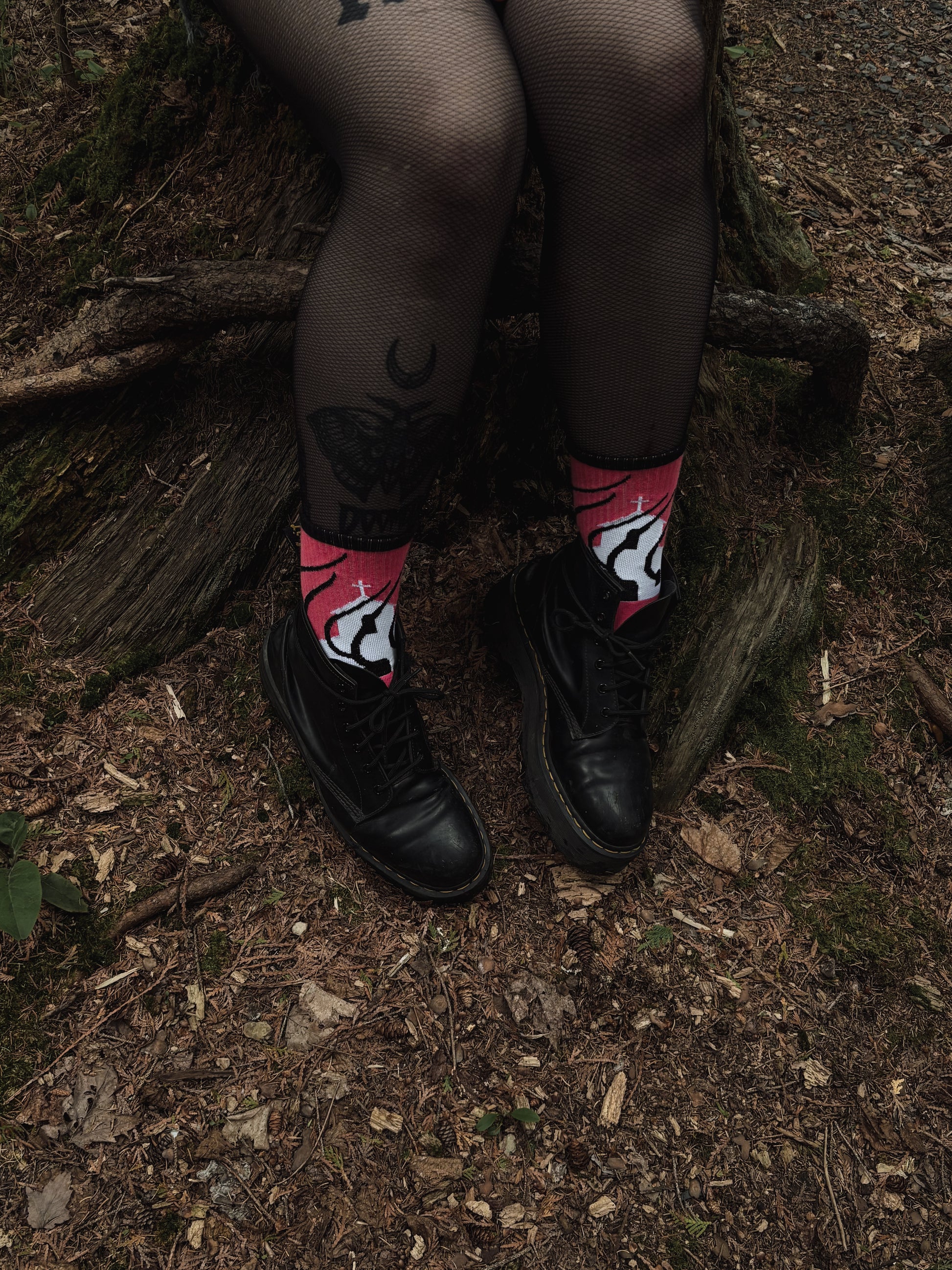 Hot pink socks featuring a flaming church design. Styled with fishnets and platform shoes, walking through mossy woods. A bold statement of queer defiance.