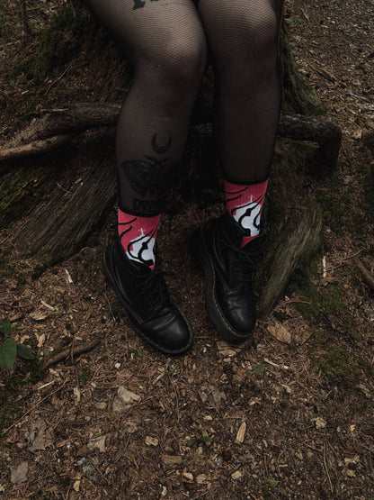 Hot pink socks featuring a flaming church design. Styled with fishnets and platform shoes, walking through mossy woods. A bold statement of queer defiance.